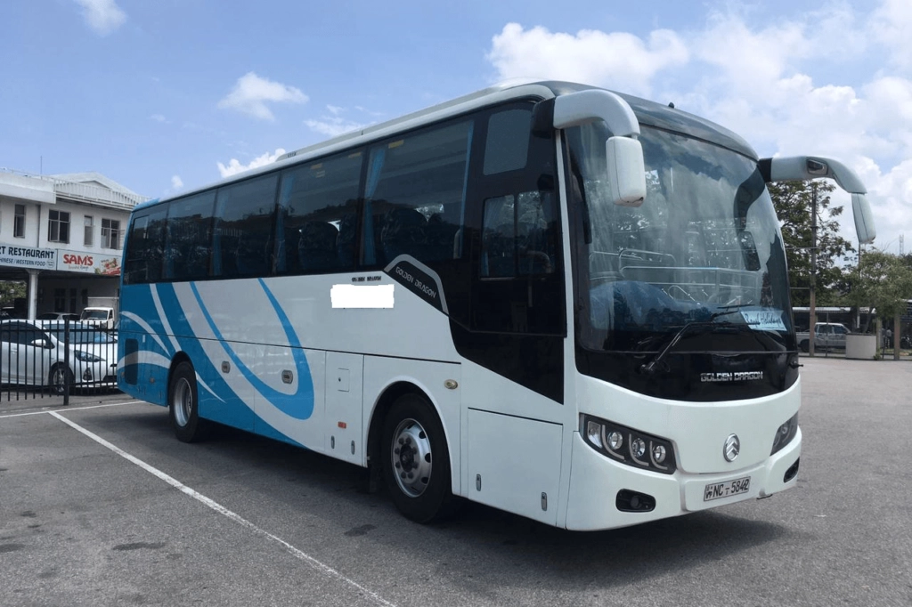 A large, white, and blue luxury coach bus is parked at Zohorul Rent A Car